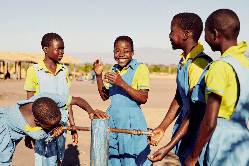 Children using a community water pump